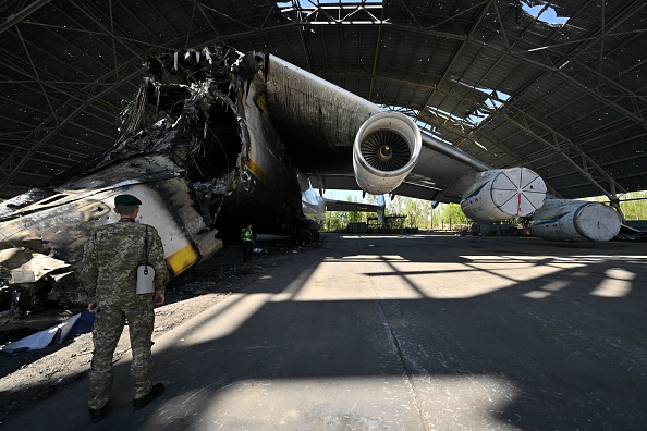 Un militaire regarde un avion cargo ukrainien Antonov An-225 "Mriya" détruit lors de l'invasion russe de l'Ukraine en mai 2022 (SERGEI SUPINSKY/AFP via Getty Images)
