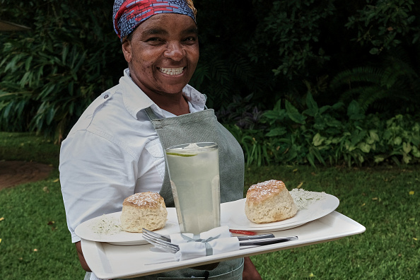 Une serveuse de Bottom Drawer, un salon de thé haut de gamme à Harare, porte des scones fraîchement cuits à Harare, le 16 février 2023. (JEKESAI NJIKIZANA/AFP via Getty Images)