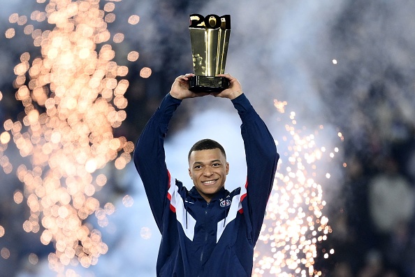 L'attaquant du Paris Saint-Germain Kylian Mbappé soulève un trophée lors d'une cérémonie après être devenu le meilleur buteur de l'histoire du Paris Saint-Germain avec son 201e but le 4 mars 2023. (FRANCK FIFE/AFP via Getty Images)