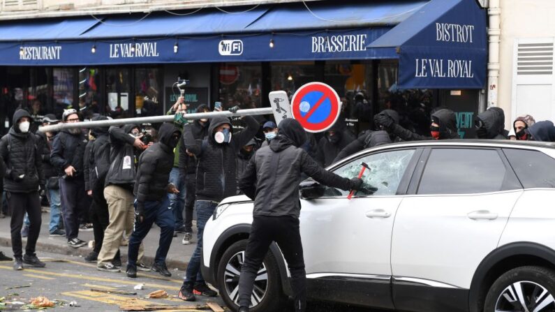 Des black blocs utilisent un marteau et un panneau pour casser une voiture à Paris, le 7 mars 2023. (Photo: ALAIN JOCARD/AFP via Getty Images)