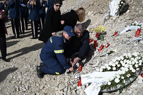 Un pompier allume une bougie lors d'une prière commémorative le 9 mars 2023, sur le site de l'accident de train qui a fait 57 morts le 28 février, dans la pire catastrophe ferroviaire de Grèce. (SAKIS MITROLIDIS/AFP via Getty Images)