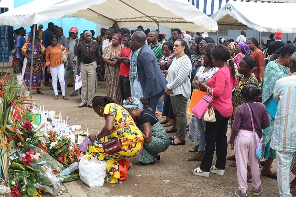Des amis et des parents s'inclinent devant les photos et les noms des disparus d'un naufrage à Libreville, au Gabon. (STEEVE JORDAN/AFP via Getty Images)