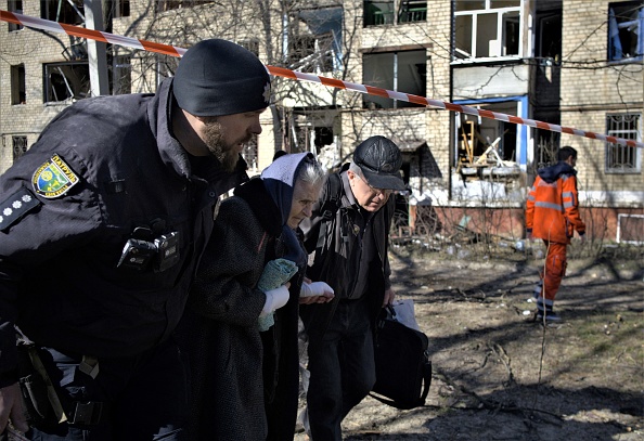 Un officier de police ukrainien évacue une femme âgée blessée après un bombardement dans la ville de Kramatorsk, le 14 mars 2023. (SERGEY SHESTAK/AFP via Getty Images)