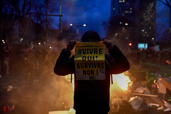 Un manifestant tient une pancarte lors d'une manifestation près de la Place d'Italie à Paris, le 18 mars 2023, contre le gouvernement qui a promulgué l'article 49.3. (JULIEN DE ROSA/AFP via Getty Images)