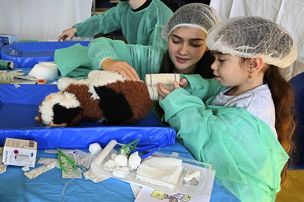 Une petite fille soigne son doudou avec une étudiante en médecine à l'hôpital des nounours de la faculté de médecine de Strasbourg. (FRÉDÉRICK FLORIN/AFP via Getty Images)