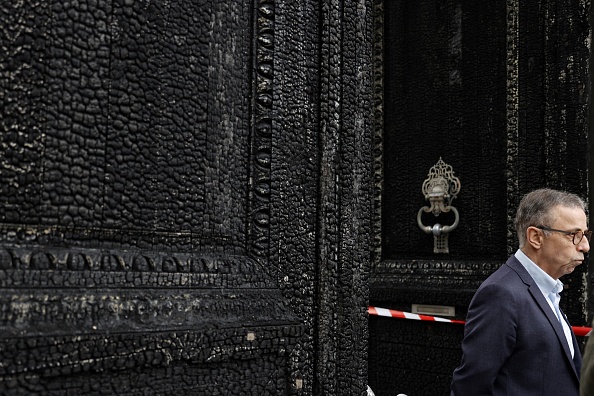 Le maire de Bordeaux, Pierre Hurmic, se tient devant la porte brûlée de l'hôtel de ville de Bordeaux, le 24 mars 2023, au lendemain de l'incendie. (ROMAIN PERROCHEAU/AFP via Getty Images)