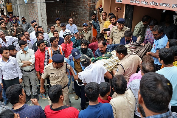 Des secouristes et des agents de sécurité transportent sur un brancard un fidèle blessé après l'effondrement du plancher d'un puits dans un temple d'Indore, en Inde, le 30 mars 2023. (-/AFP via Getty Images)