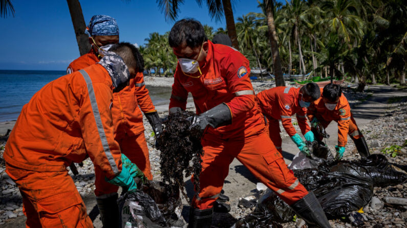 Les gardes-côtes  et les pêcheurs nettoient une nappe de pétrole qui s'est échouée sur le rivage du pétrolier MT Princess Empress, le 08 mars 2023, aux Philippines. (Photo Ezra Acayan/Getty Images)