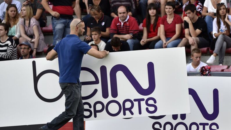 Un homme déplace un panneau publicitaire bein sports. (PASCAL PAVANI/AFP via Getty Images)