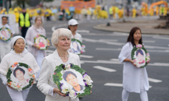 Des pratiquants de Falun Dafa portent des photos des victimes de la persécution en Chine lors d'une marche dans le centre de Varsovie, en Pologne, le 9 septembre 2022. (Mihut Savu/Epoch Times)