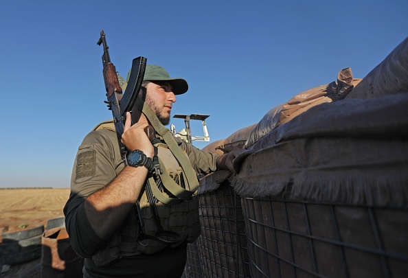 Un combattant soutenu par la Turquie regarde depuis une position militaire dans la zone syrienne de Jibrin, dans la campagne orientale d'Alep, en direction de la zone contrôlée par les Kurdes de Tal Rifaat, le 19 juillet 2022. (BAKR ALKASEM/AFP via Getty Images)