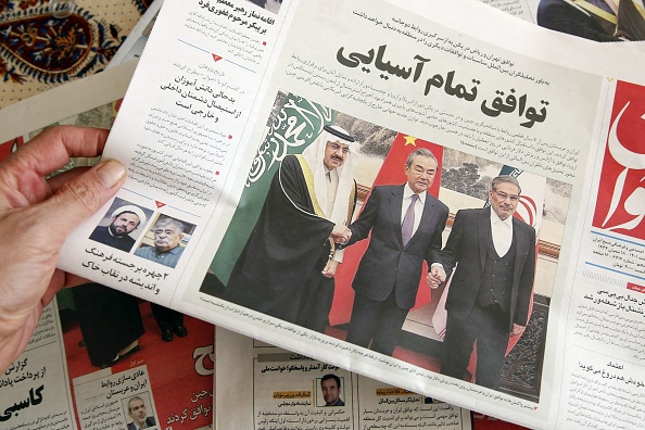 À Téhéran, un homme tient un journal local qui affiche en première page l'accord conclu entre l'Iran et l'Arabie saoudite signé la veille à Pékin, le 11 mars 2023. (ATTA KENARE/AFP via Getty Images)