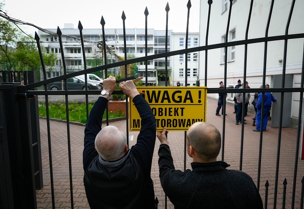 Des fonctionnaires municipaux placent un panneau d'avertissement sur le portail d'un ancien lycée russe à Varsovie, en Pologne, le 29 avril 2023. (JAAP ARRIENS/AFP via Getty Images)