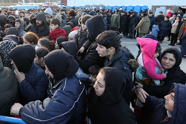 Des migrants font la queue devant le centre de transport et de logistique près du poste frontière de Bruzgi, à la frontière entre la Biélorussie et la Pologne, le 20 novembre 2021. (Photo MAXIM GUCHEK/BELTA/AFP via Getty Images)