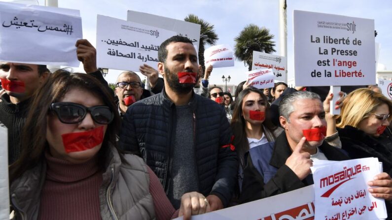 Des journalistes tunisiens se couvrent la bouche avec du ruban adhésif rouge alors qu'ils manifestent devant le bureau du Premier ministre dans la capitale Tunis le 16 février 2023, pour défendre la liberté d'expression et contre la persécution des journalistes. (Photo FETHI BELAID/AFP via Getty Images)