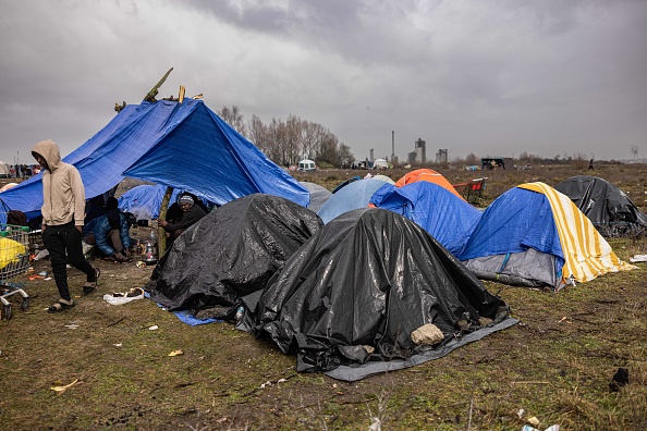 Des migrants assis sous une tente dans un camp de fortune à Mardyck, le 9 mars 2023. (SAMEER AL-DOUMY/AFP via Getty Images)