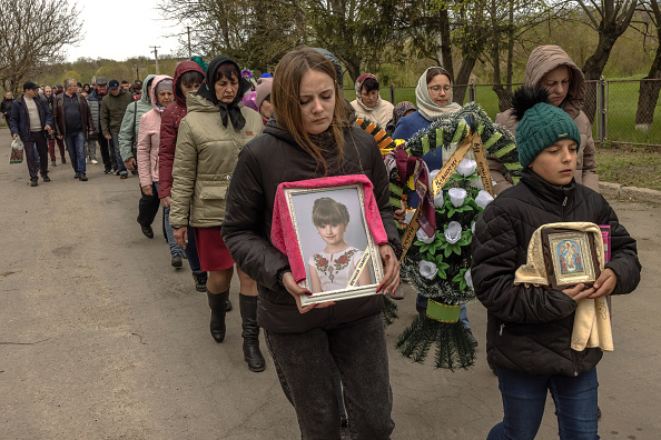 Une femme porte le portrait de l'enfant Uliana Troichuk (8), tuée lors de l'attaque russe sur un immeuble résidentiel, lors de ses funérailles le 30 avril 2023 dans le village d'Apolyanka, en Ukraine. (Roman Pilipey/Getty Images)