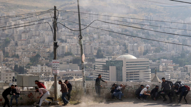 Des manifestants palestiniens s'abritent au milieu des affrontements avec les forces de sécurité israéliennes lors d'un raid dans la vieille ville de Naplouse, en Cisjordanie occupée, le 9 mai 2023. (Photo JAAFAR ASHTIYEH/AFP via Getty Images)