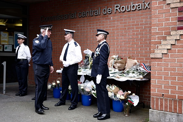 Le directeur général de la police nationale, Frédéric Veaux (2e à g.), salue un mémorial improvisé devant un commissariat de Roubaix, le 23 mai 2023. (SAMEER AL-DOUMY/AFP via Getty Images)
