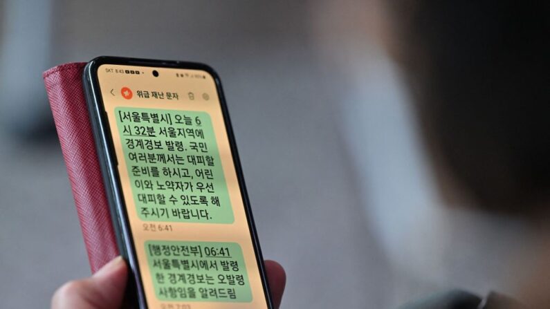 Une femme montre son téléphone portable avec un message d'alerte d'évacuation d'urgence émis par la ville de Séoul le 31 mai 2023. (Photo JUNG YEON-JE/AFP via Getty Images)