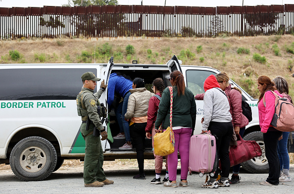Les immigrants sont transportés d'un camp de fortune situé entre les murs de la frontière entre les États-Unis et le Mexique, le 13 mai 2023 à San Diego, en Californie. (Mario Tama/Getty Images)