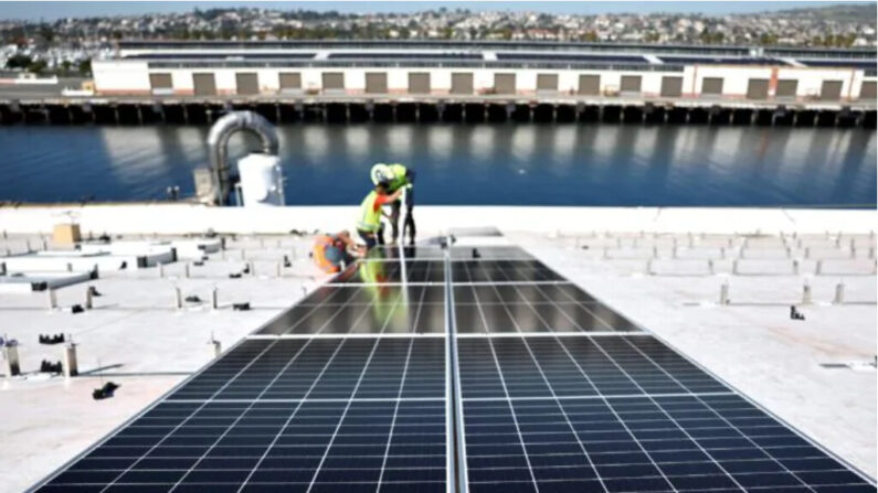 Des ouvriers installent des panneaux solaires pendant la phase d'achèvement d'un toit solaire de 4 acres au sommet du centre de recherche et de développement d'AltaSea au port de Los Angeles, le 21 avril 2023. (Mario Tama/Getty Images)