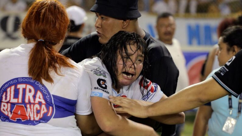 TOPSHOT - A woman is held by other as she cries following a stampede during a football match between Alianza and FAS at Cuscatlan stadium in San Salvador, on May 20, 2023. Nine people were killed May 20, 2023 in a stampede at an El Salvador stadium where soccer fans "Le football salvadorien est en deuil" après une bousculade qui a fait douze morts samedi soir dans un stade de la capitale. (Photo by MILTON FLORES/AFP via Getty Images)