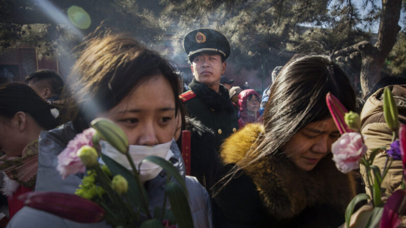 Un officier de police paramilitaire surveille des fidèles chinois qui prient au temple Yongchegong Lama à Pékin, en Chine, le 8 février 2016. (Kevin Frayer/Getty Images)