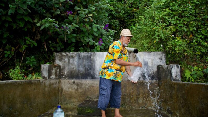 Un habitant remplit un récipient avec de l'eau provenant d'une source naturelle à Trois-Rivières sur l'île française d'outre-mer de la Guadeloupe, le 26 juillet 2018. (Photo CEDRICK ISHAM CALVADOS/AFP via Getty Images)