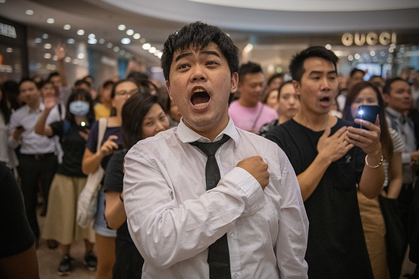 Un manifestant tient sa main contre sa poitrine tout en chantant l'« hymne » de protestation « Glory to Hong Kong » en 2019. (Carl Court/Getty Images)