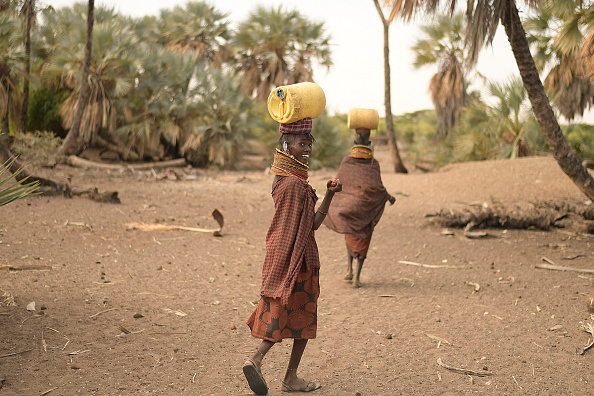 Des femmes Turkana transportent des jerrycans remplis d'eau à Loiyangalani où sont hébergées les familles touchées par la sécheresse prolongée, à Marsabit, dans le nord du Kenya, le 11 juillet 2022. (SIMON MAINA/AFP via Getty Images)