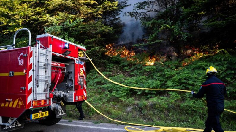Un pompier déroule une lance près d'un feu de forêt à Bois-de-Champ, le 13 juin 2023. (Photo SEBASTIEN BOZON/AFP via Getty Images)