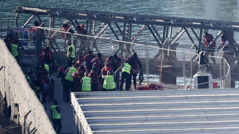 Des migrants sont escortés par les forces frontalières britanniques à la marina de Douvres, dans le sud-est de l'Angleterre, le 15 juin 2023, après avoir été récupérés en mer alors qu'ils tentaient de traverser la Manche. (HENRY NICHOLLS/AFP via Getty Images)