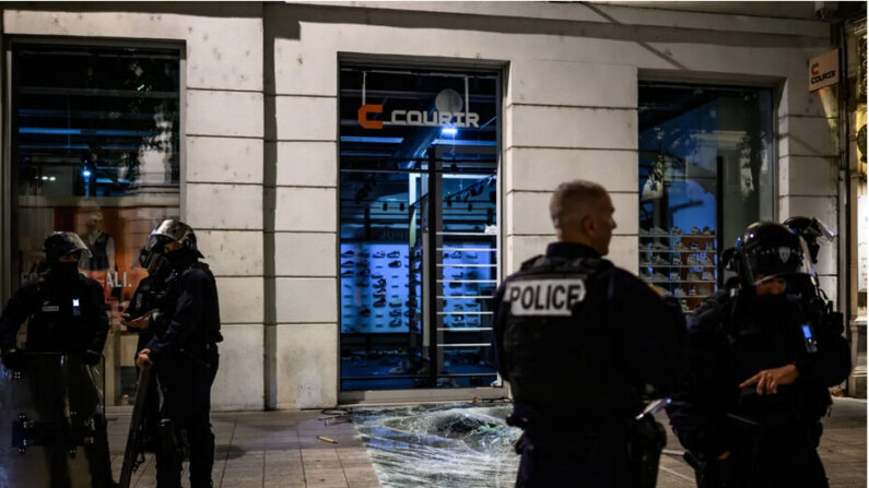 Des policiers se tiennent devant un magasin pillé lors d'affrontements avec la police à Lyon, dans le sud-est de la France, le 30 juin 2023, trois jours après qu'un jeune homme de 17 ans a été abattu d'une balle dans la poitrine par la police à bout portant à Nanterre, dans la banlieue ouest de Paris. (Jeff Pachoud /AFP via Getty Images)
