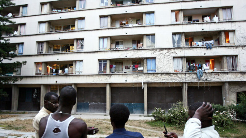 Un groupe de personnes discute devant un immeuble abritant un squat géant à Cachan, dans la banlieue sud de Paris, en juillet 2006. (Photo : FRED DUFOUR/AFP via Getty Images)