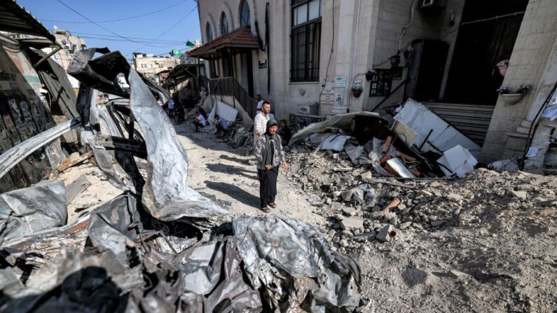 Le 5 juillet 2023 des personnes se tiennent près des décombres et des restes d'un véhicule détruit, dans la ville de Jénine, en Cisjordanie occupée, après que l'armée israélienne a déclaré la fin d'une opération militaire de deux jours dans la région. (Photo AHMAD GHARABLI/AFP via Getty Images)