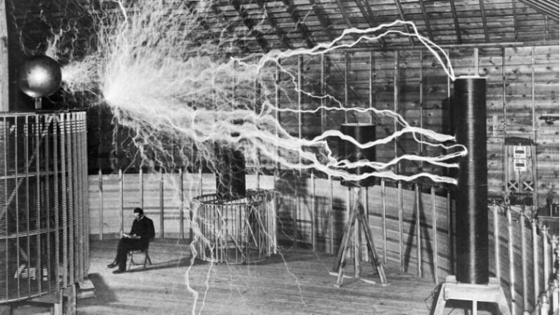 Nikola Tesla dans son laboratoire de Colorado Springs (États-Unis, décembre 1899). La photo est une exposition multiple, Tesla n'était pas dans la pièce pendant les décharges d'éclairs. (Dickenson V. Alley, vers 1899/domaine public)