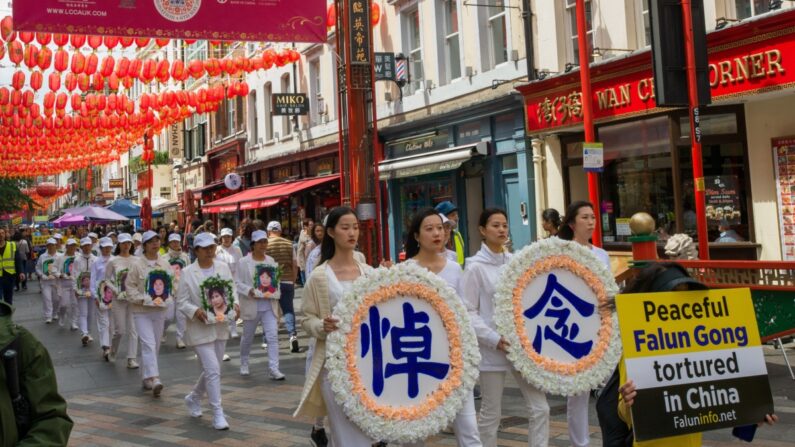 Des pratiquants de Falun Gong tiennent des couronnes funéraires et des portraits de pratiquants tués en Chine, lors d'un rassemblement marquant le 24e anniversaire de la persécution menée par le PCC contre le Falun Gong, à Londres, le 15 juillet 2023. (Yanning Qi/Epoch Times)