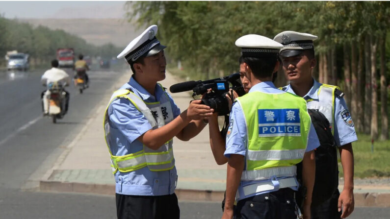 La police chinoise arrête un journaliste à un poste de contrôle sur la route de la ville ouïghoure de Lukqun, dans la région du Xinjiang, le 28 juin 2013. (Mark Ralston/AFP via Getty Images)
