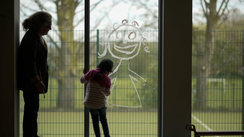 Une jeune fille peint une image d'elle-même sur la fenêtre de l'école alors que les enfants des travailleurs clés participent à des activités scolaires à l'école primaire Oldfield Brow à Altrincham, en Angleterre, le 8 avril 2020. (Christopher Furlong/Getty Images)