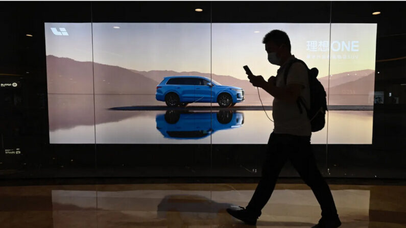 Un homme passe devant un panneau d'affichage présentant un nouveau modèle du constructeur chinois de voitures électriques Li Auto, dans un centre commercial de Pékin, le 12 août 2021. (Jade Gao/AFP via Getty Images)