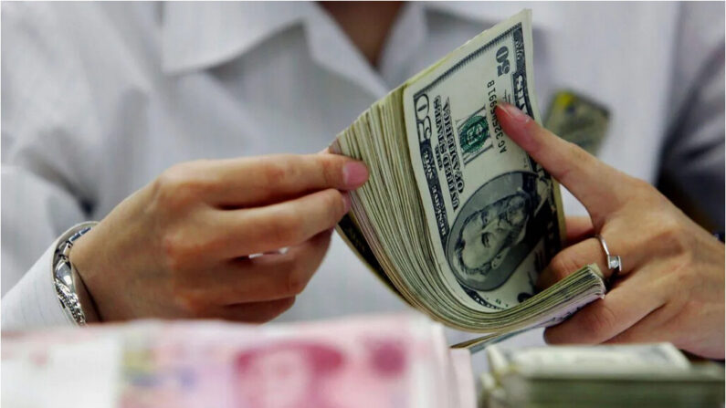 Un guichetier compte la pile de yuans chinois et de dollars américains dans une banque de Shanghai, en Chine, le 22 juillet 2005. (STR/AFP/Getty Images)