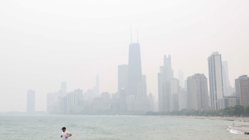 Un homme fait son jogging le long du lac Michigan, en arrière-plan une épaisse fumée provenant des incendies de forêt au Canada, à Chicago, le 27 juin 2023. (Kamil Krzaczynski/AFP via Getty Images)