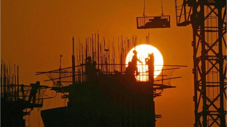 Des ouvriers chinois travaillent sur un chantier de construction au coucher du soleil à Chongqing, en Chine, le 6 mars 2005. (China Photos/Getty Images)