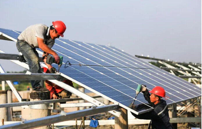 Des ouvriers installent des panneaux solaires sur le site de construction de la centrale photovoltaïque à Huai'an, en Chine, le 11 juin 2018. (VCG/VCG via Getty Images)
