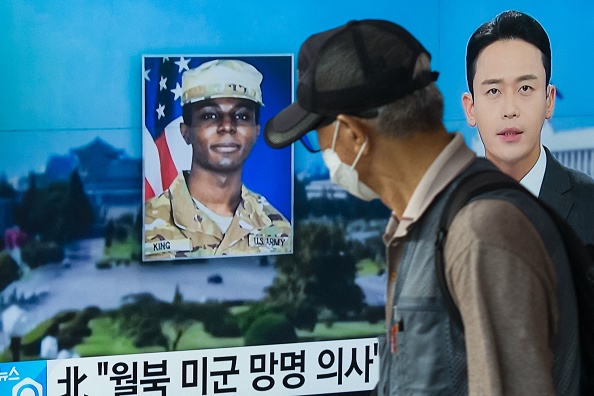 Sur cette photo prise à Séoul le 16 août 2023, un homme passe devant un téléviseur diffusant une photo du soldat américain Travis King (au c.). (Photo ANTHONY WALLACE/AFP via Getty Images)