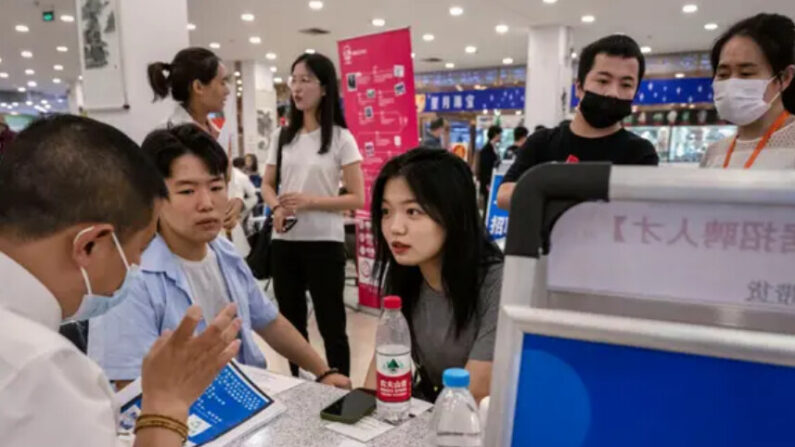 Un jeune homme et une jeune femme discutent avec un recruteur alors qu'ils cherchent un emploi lors d'un salon de l'emploi, le 9 juin 2023 à Pékin, en Chine. (Kevin Frayer/Getty Images)