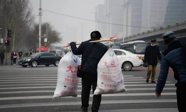 Un travailleur migrant traverse une route après être arrivé à bord d'un bus longue distance à Pékin, le 10 mars 2021. (Greg Baker/AFP via Getty Images)