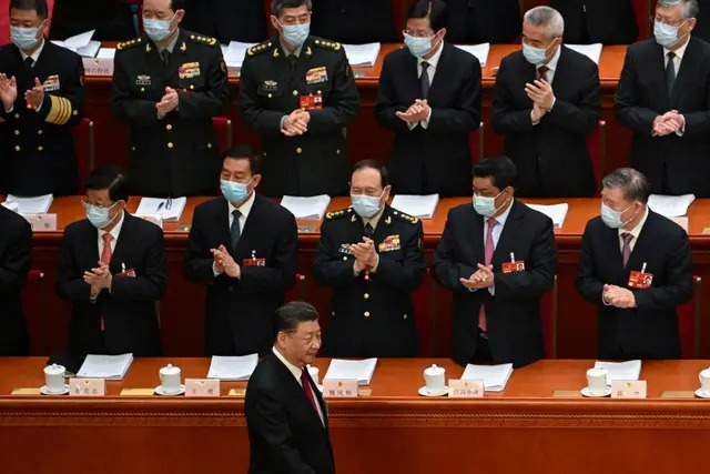 Des délégués applaudissent le dirigeant chinois Xi Jinping (en bas) à son arrivée pour la session d'ouverture de l'Assemblée nationale populaire (ANP), au Grand Hall du Peuple à Pékin, le 5 mars 2023. (Noel Celis/AFP via Getty Images)