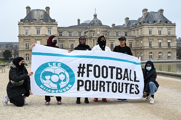 Des Hijabeuses posent avec une banderole "#football pour tous" dans le jardin du Luxembourg face au Sénat français à Paris, le 26 janvier 2022.   (BERTRAND GUAY/AFP via Getty Images)